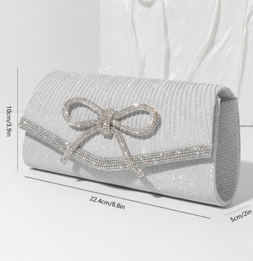 Silver clutch bag with a bow and measurements on a white background
